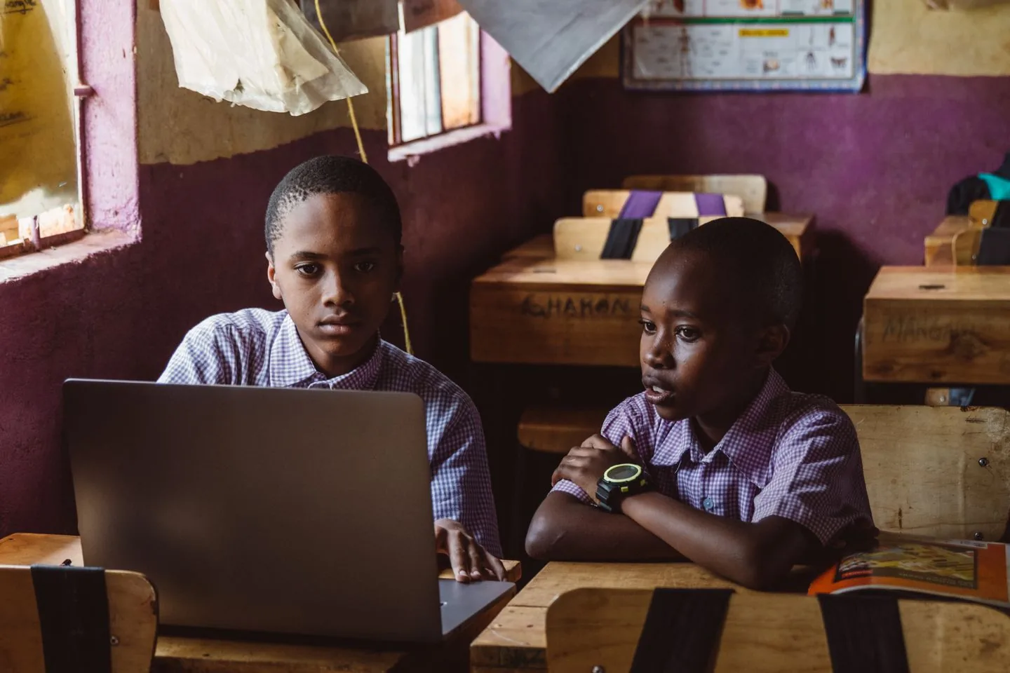 Two students in school uniforms learning together on a laptop